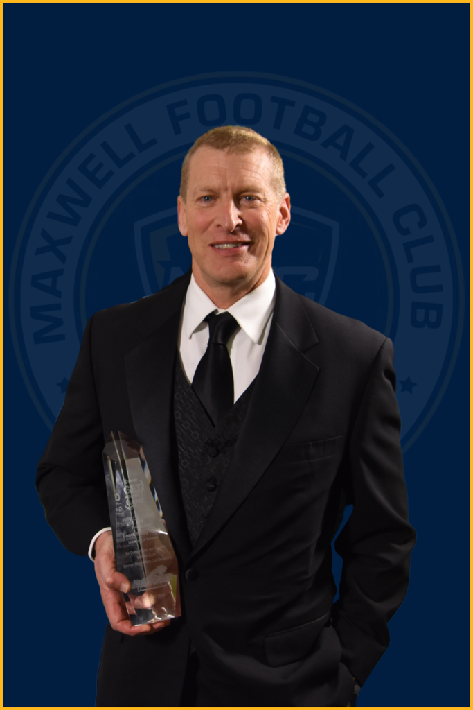 The Andy Talley Get In The Game Impact Award being held by the award's 2023 winner, Montana Head Coach Bobby Hauck