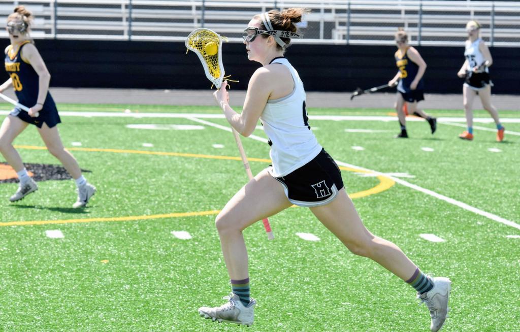 Minneapolis Girls High School Lacrosse player streaks up the sideline during a game