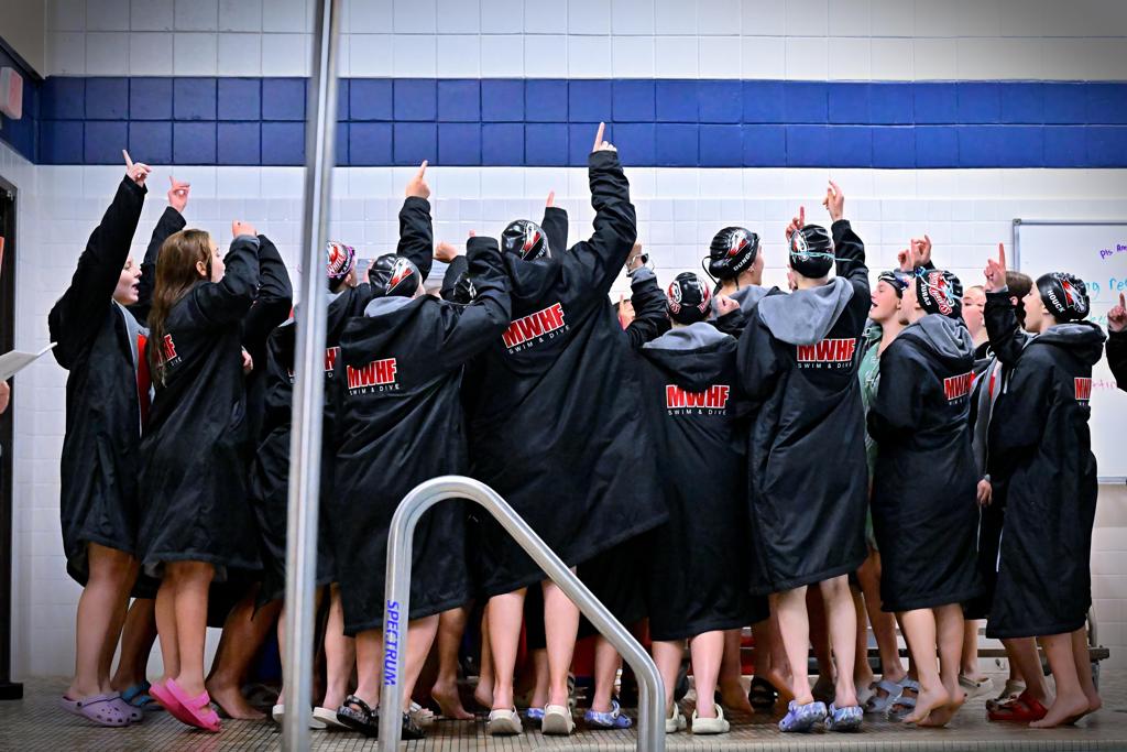 girls swim team celebrating on pool deck