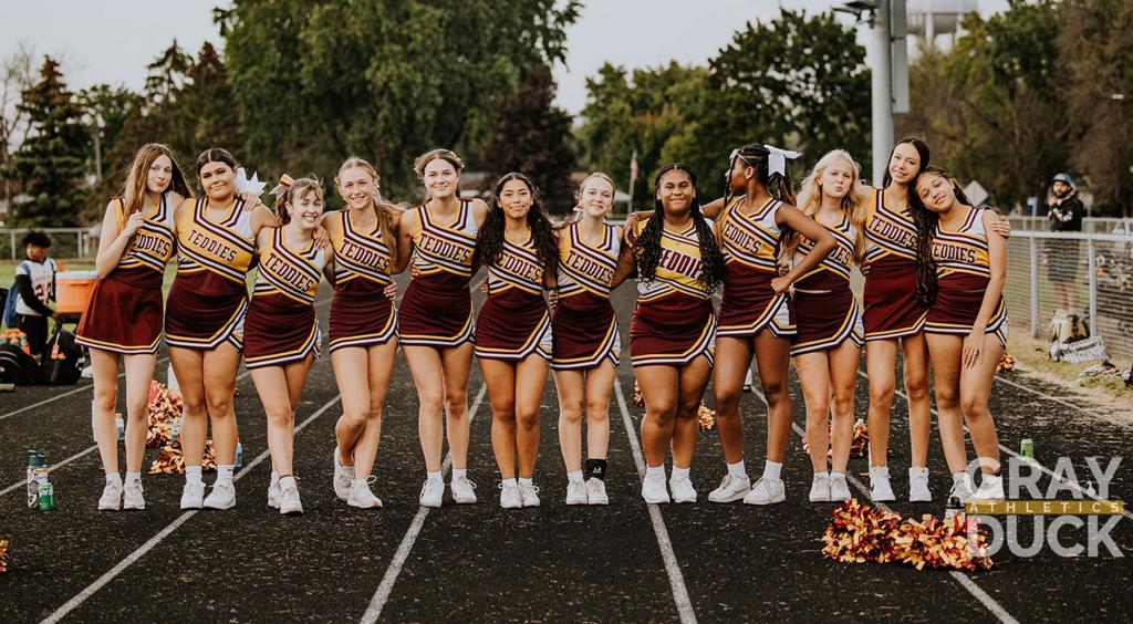 Roosevelt High School Cheer Squad in a single line on the track of the Brooklyn Center High School football stadium during a game