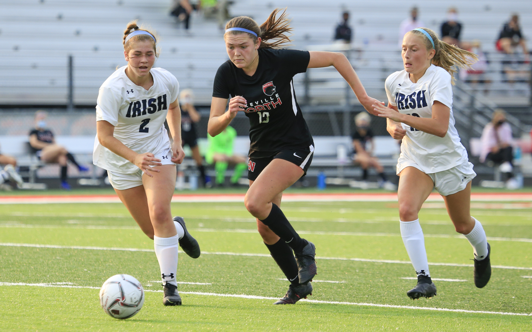 Lakeville North’s Abby Ruhland (13) attempts to outrun Rosemount’s Joey Edgar (left) and Ashley Herold (right) during Tuesday evening’s game. The Panthers and Irish played to a 0-0 draw at Lakeville North High School. Photo by Jeff Lawler, SportsEngine