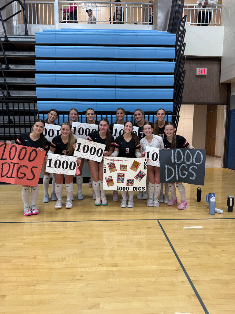 volleyball team holding "1,000 digs" signs