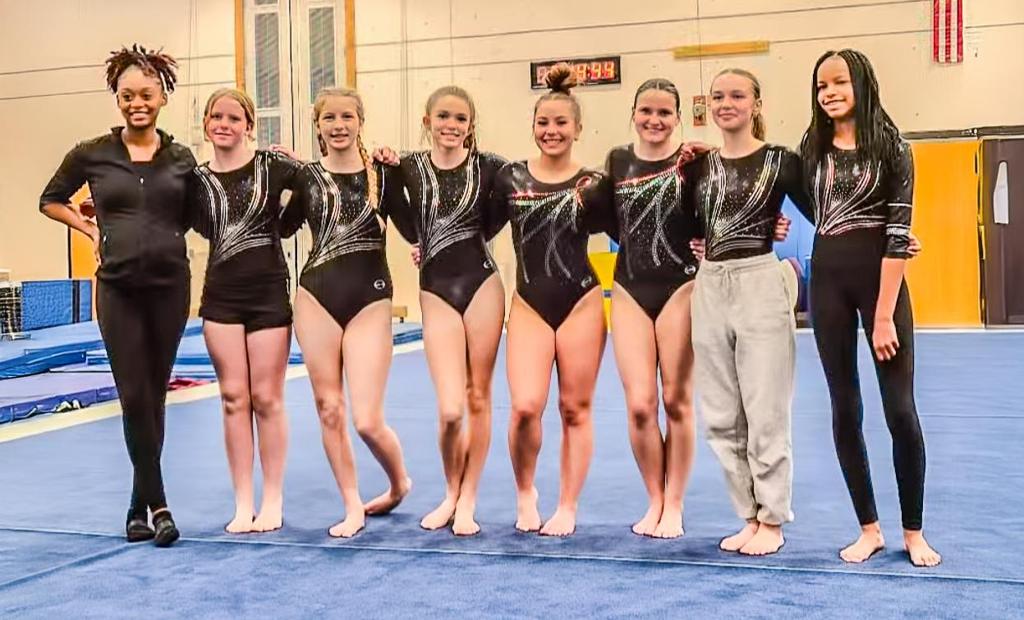 Image of a Minneapolis Roosevelt High School gymnastic team lined in a row on the mat at a meet