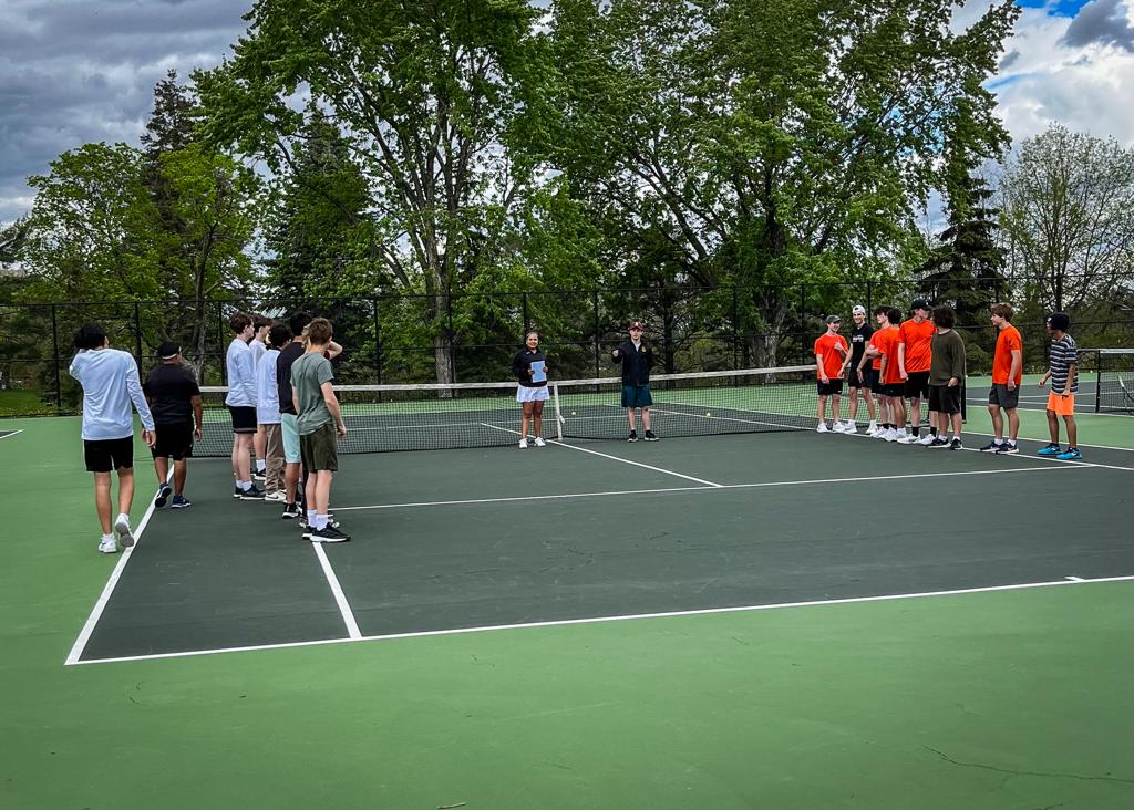 Minneapolis Roosevelt Boys Tennis team gathers on the court with Minneapolis South players at the start of a match