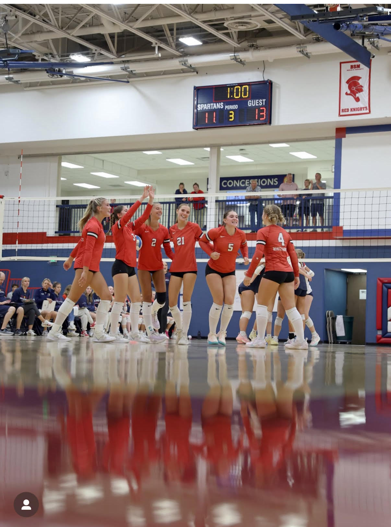 volleyball team celebrates on floor